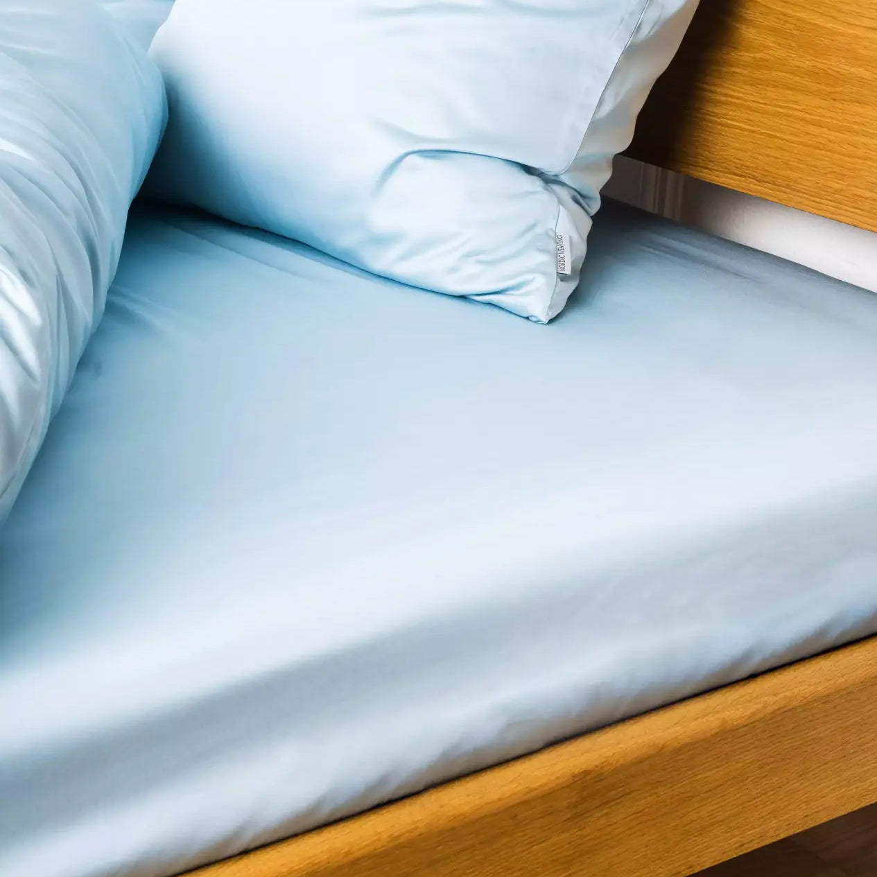 Miljøbillede af seng redt med bambus kuvertlagen i farven lys blå i størrelsen 180x200x20cm