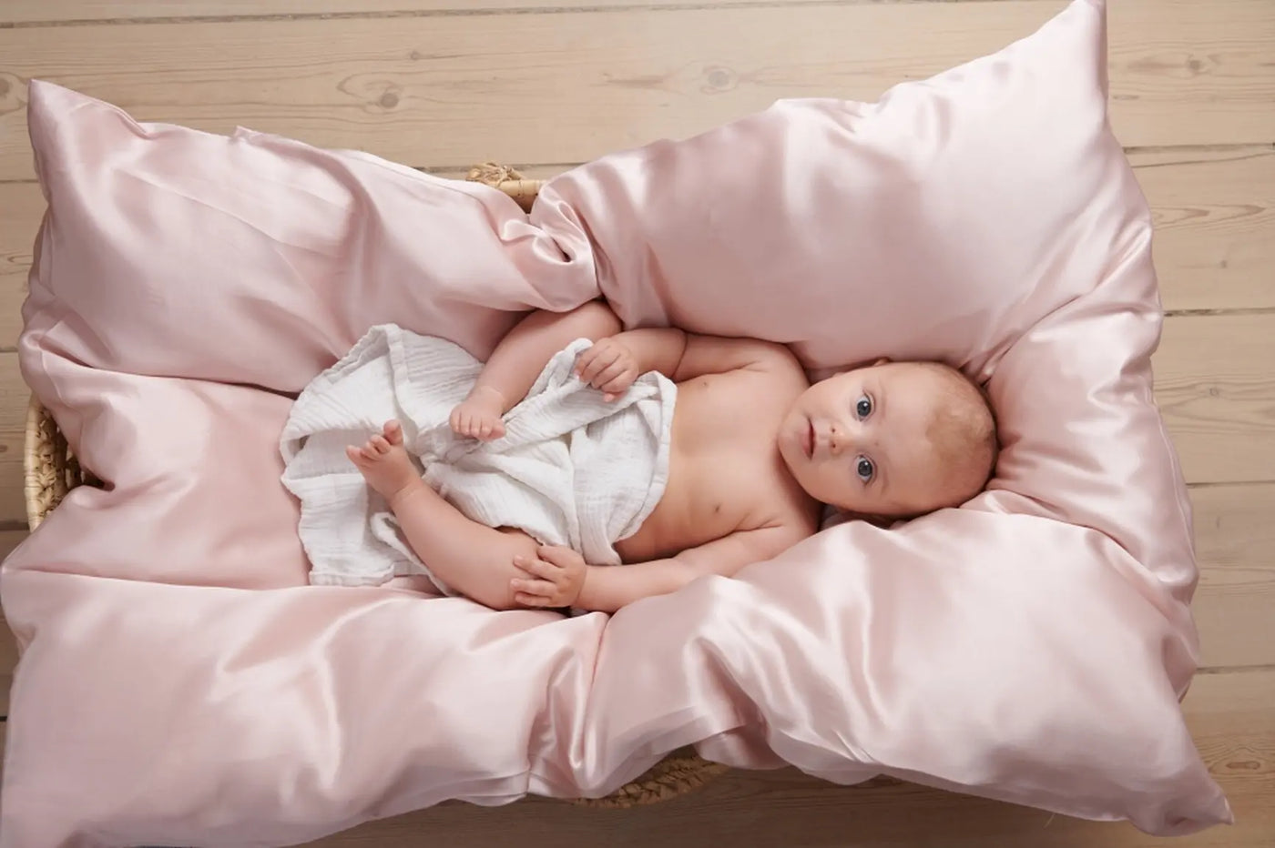 Miljøbillede af baby i en seng med børne silkesengetøj i farven rose 